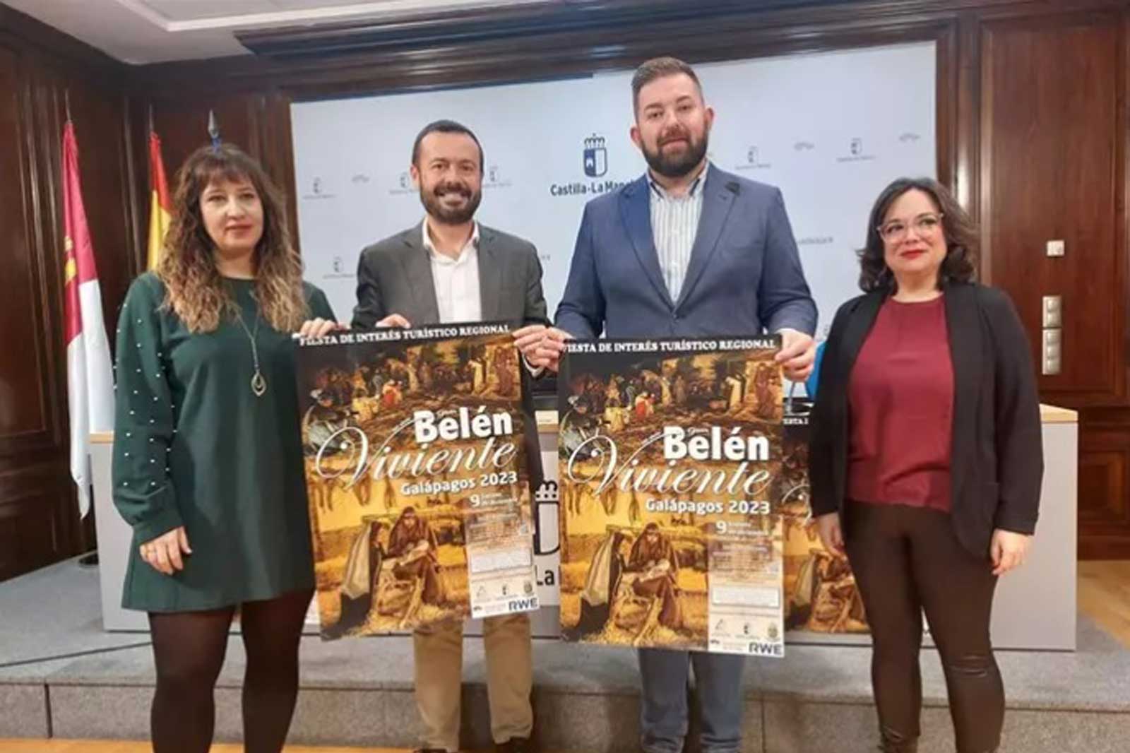 Cuatro personas sostienen carteles promocionales del evento 'Belén Viviente' en Galápagos 2023, en un fondo formal.