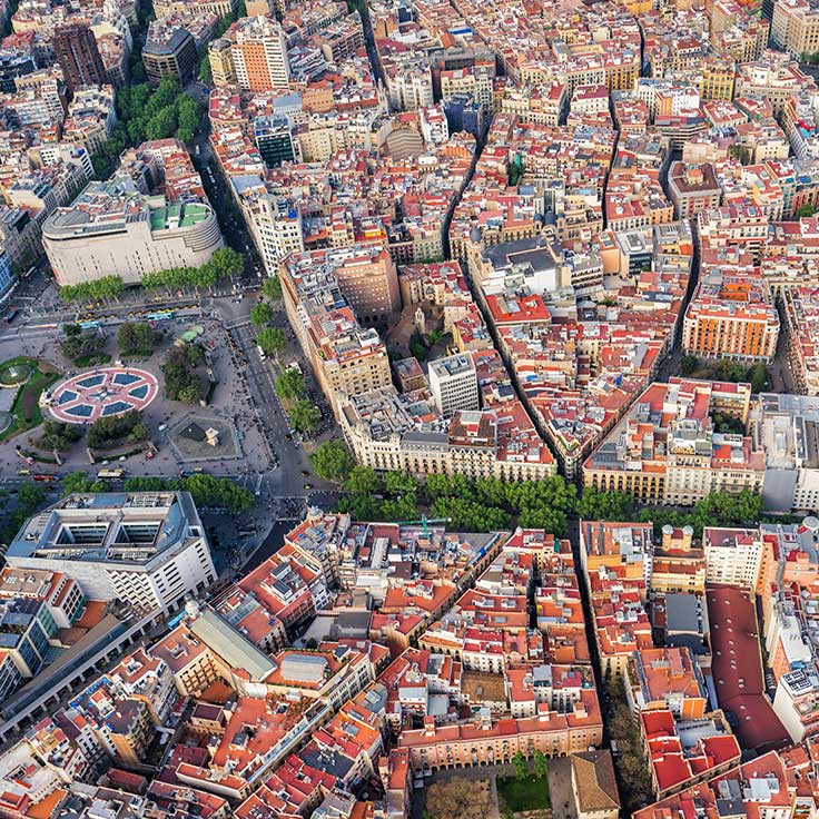Aerial view of a densely built urban area with varied rooftops, streets, and greenery in Barcelona.