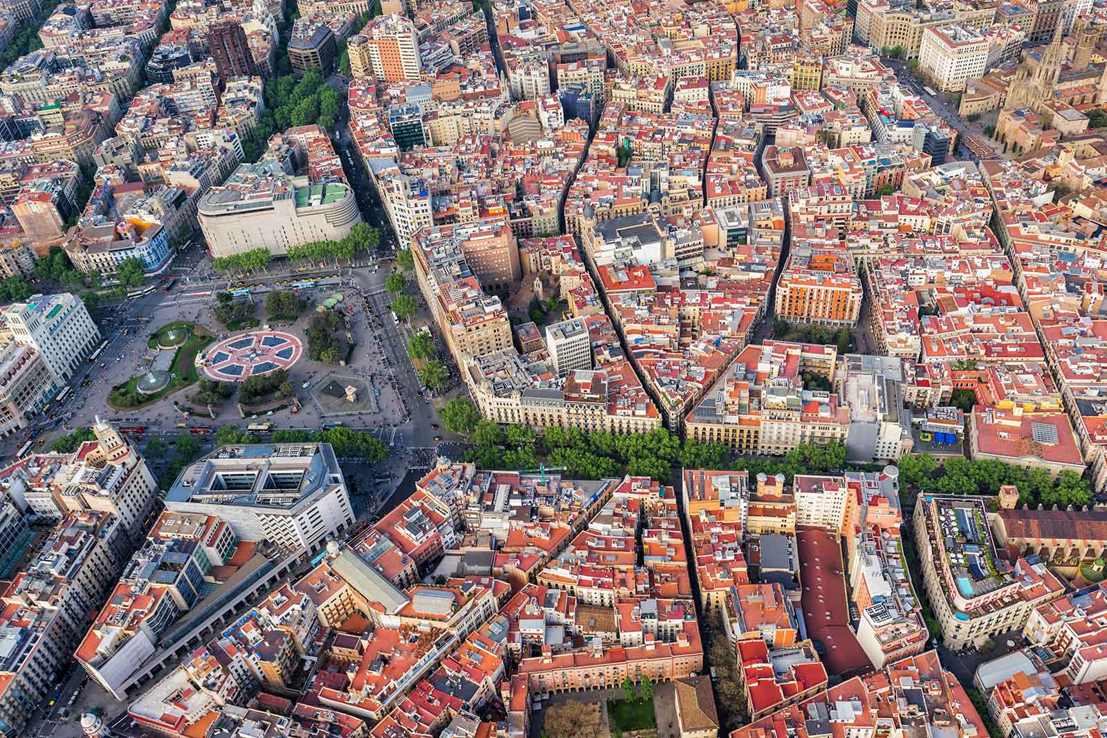 Vista aérea de Barcelona que muestra intrincados diseños de calles y vibrantes edificios con techos rojos.